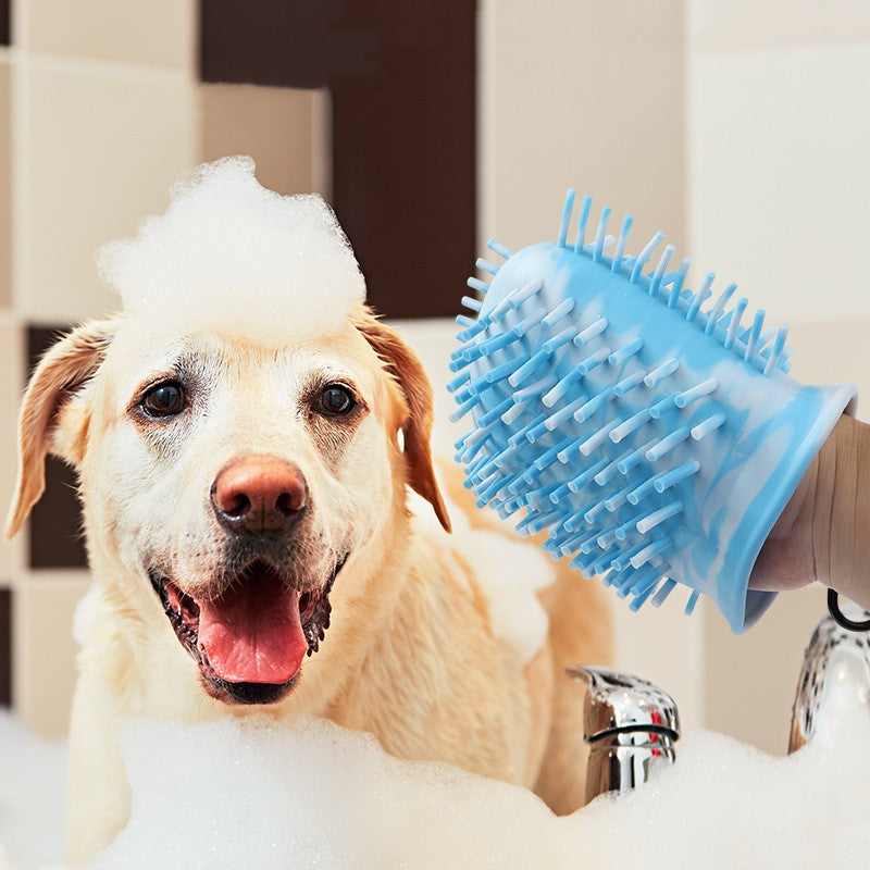 Dog being bathed with a blue pet grooming brush in a bathroom setting.